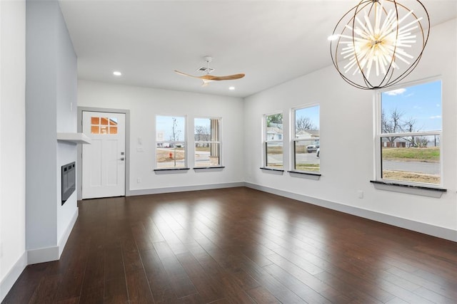 unfurnished living room with heating unit, dark hardwood / wood-style flooring, and ceiling fan with notable chandelier