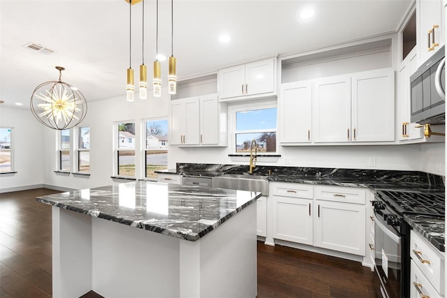 kitchen with stainless steel appliances, sink, decorative light fixtures, dark stone countertops, and white cabinetry