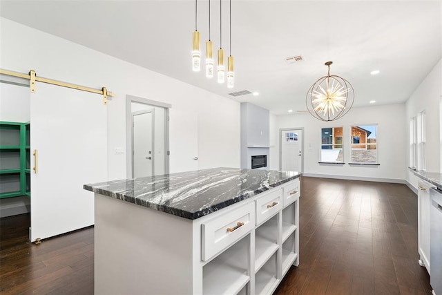 kitchen with white cabinets, pendant lighting, a barn door, and dark stone countertops