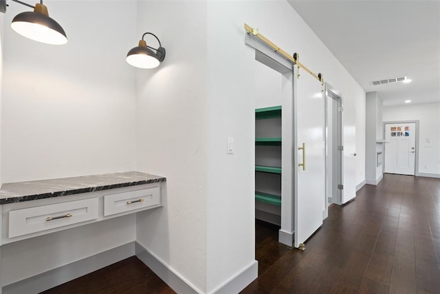 hall with a barn door and dark wood-type flooring