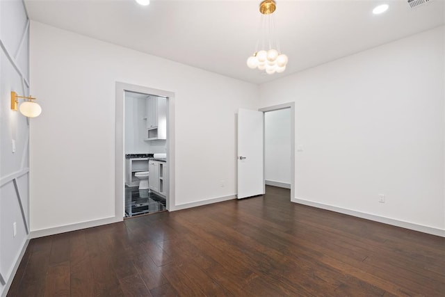 unfurnished bedroom featuring ensuite bath, a chandelier, and dark hardwood / wood-style floors