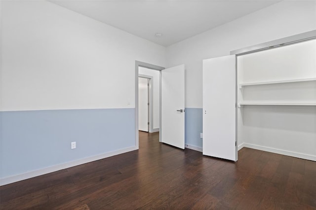 unfurnished bedroom featuring a closet and dark wood-type flooring