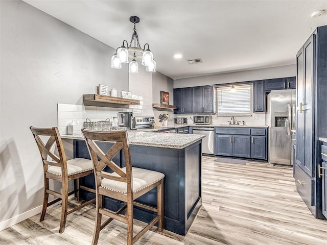 kitchen with sink, stainless steel appliances, a kitchen breakfast bar, kitchen peninsula, and pendant lighting