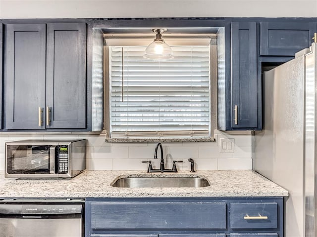 kitchen featuring sink, decorative backsplash, blue cabinetry, appliances with stainless steel finishes, and light stone counters