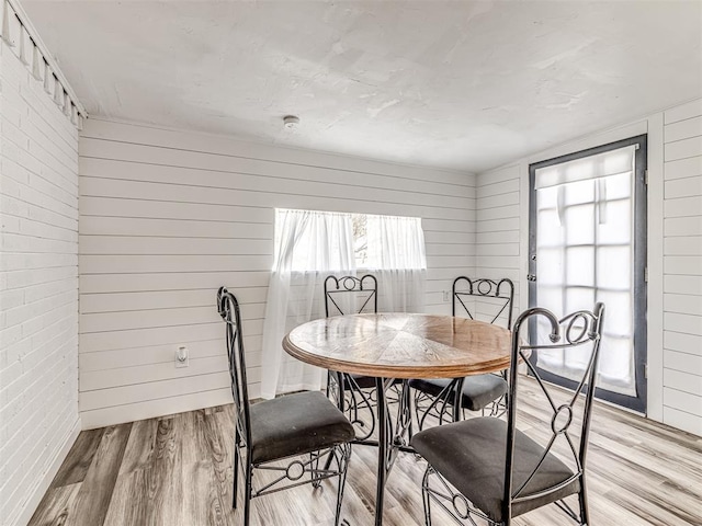 dining room featuring wood walls and light wood-type flooring