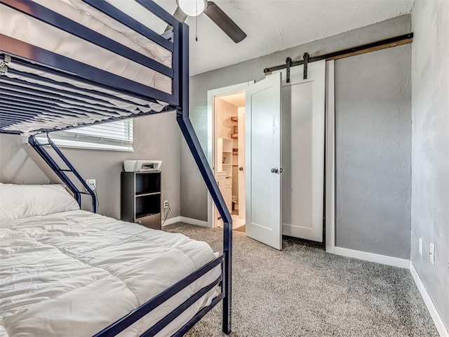 carpeted bedroom featuring a barn door, a closet, and ceiling fan