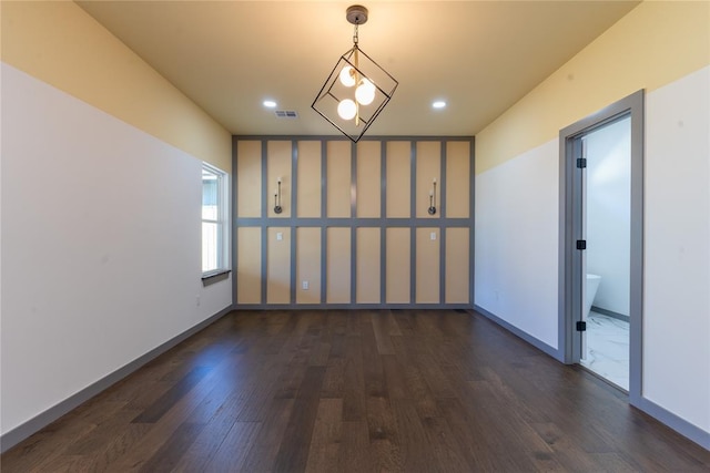 unfurnished room featuring dark hardwood / wood-style floors and an inviting chandelier