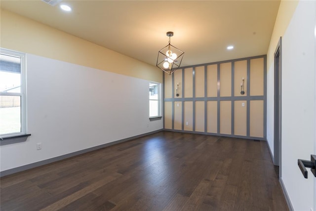 unfurnished room with an inviting chandelier and dark wood-type flooring