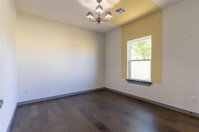 empty room with dark hardwood / wood-style floors and a notable chandelier