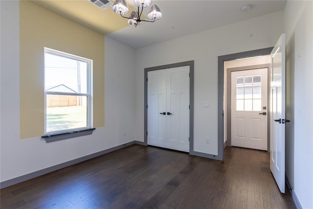 unfurnished bedroom with a closet, dark wood-type flooring, and a notable chandelier