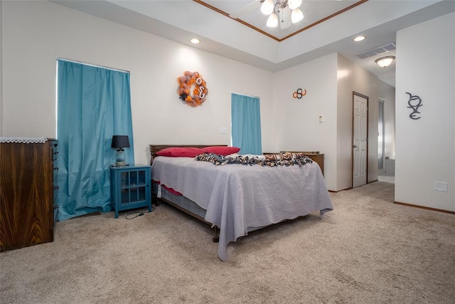 carpeted bedroom featuring ensuite bathroom, ceiling fan, and a tray ceiling