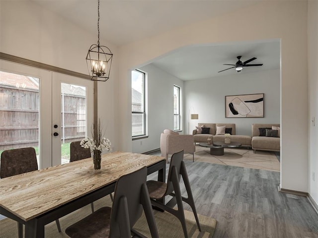 dining room with french doors, ceiling fan with notable chandelier, and hardwood / wood-style flooring