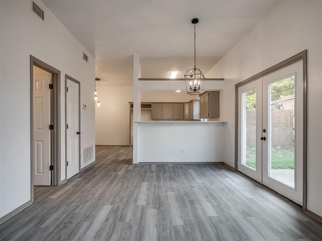 interior space with french doors, vaulted ceiling, wood-type flooring, decorative light fixtures, and a notable chandelier