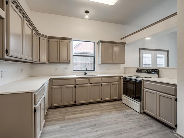 kitchen featuring sink, tasteful backsplash, gray cabinets, electric stove, and light wood-type flooring