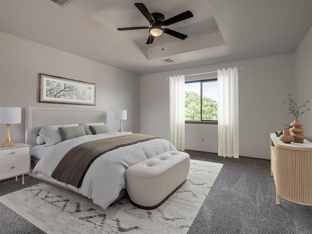 bedroom featuring dark colored carpet, ceiling fan, and a raised ceiling