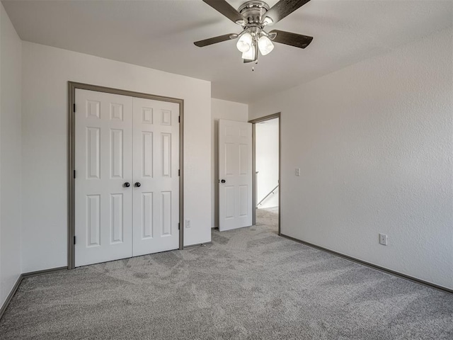 unfurnished bedroom featuring ceiling fan, a closet, and light colored carpet