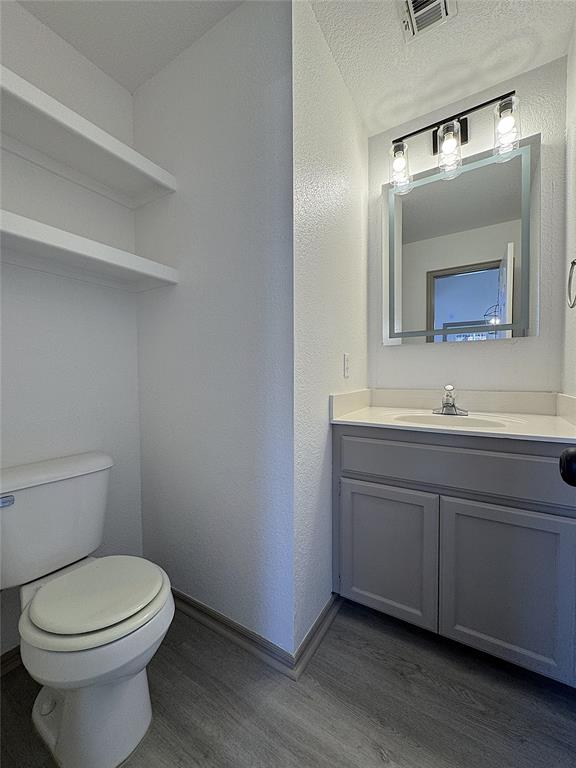 bathroom featuring hardwood / wood-style floors, vanity, a textured ceiling, and toilet