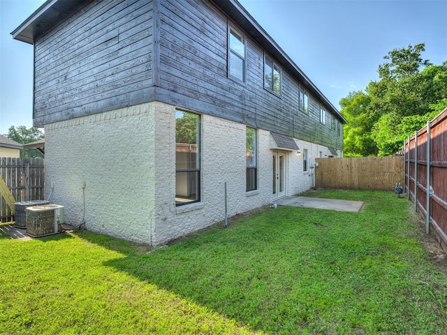 rear view of house with a lawn, a patio area, and central AC