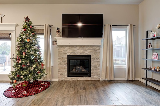 unfurnished living room with hardwood / wood-style flooring, plenty of natural light, and a stone fireplace