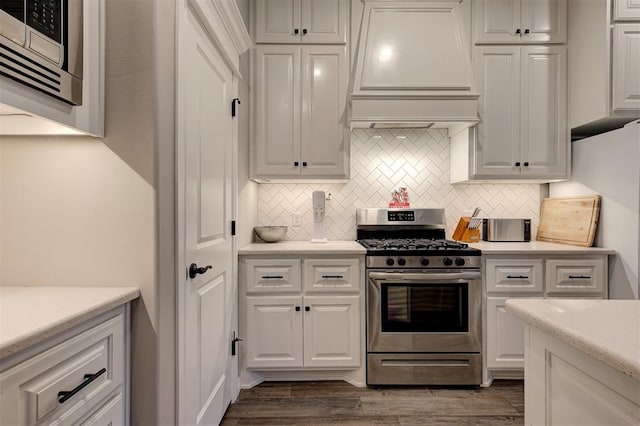 kitchen with gas range, white cabinetry, dark hardwood / wood-style floors, backsplash, and custom range hood