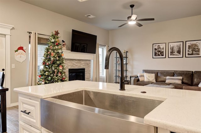 kitchen featuring light stone countertops, ceiling fan, and sink