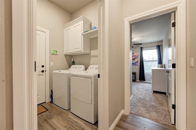 laundry area featuring washing machine and dryer, cabinets, and light hardwood / wood-style floors