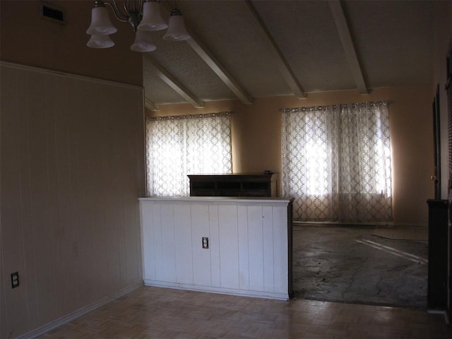 kitchen featuring parquet floors, lofted ceiling with beams, wooden walls, a healthy amount of sunlight, and a chandelier