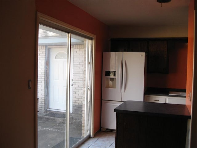 kitchen with dark brown cabinets, light tile patterned flooring, white refrigerator with ice dispenser, and sink