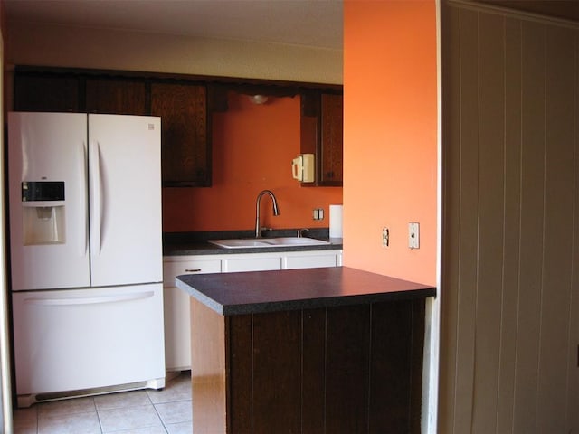 kitchen with light tile patterned floors, dark brown cabinetry, white fridge with ice dispenser, and sink