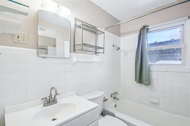 full bathroom with vanity, toilet, tile walls, and tiled shower / bath combo