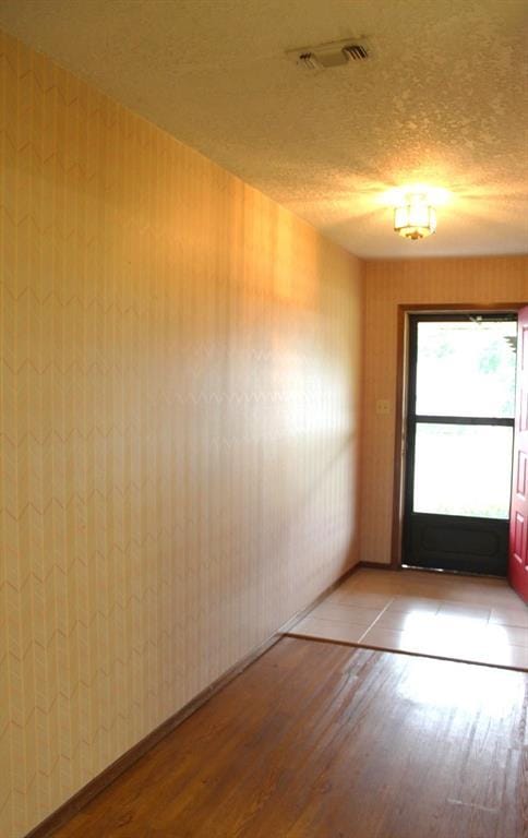 unfurnished room featuring a textured ceiling and light hardwood / wood-style flooring