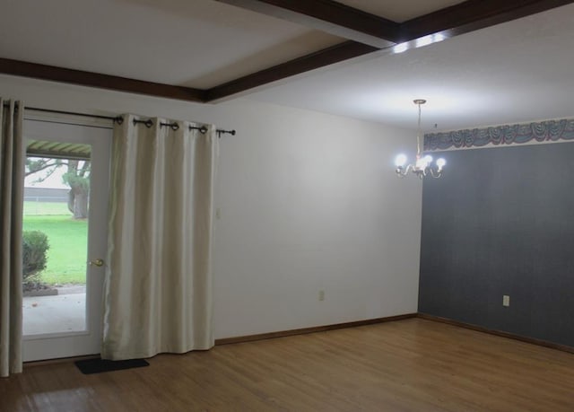 spare room featuring beamed ceiling, a notable chandelier, and wood-type flooring