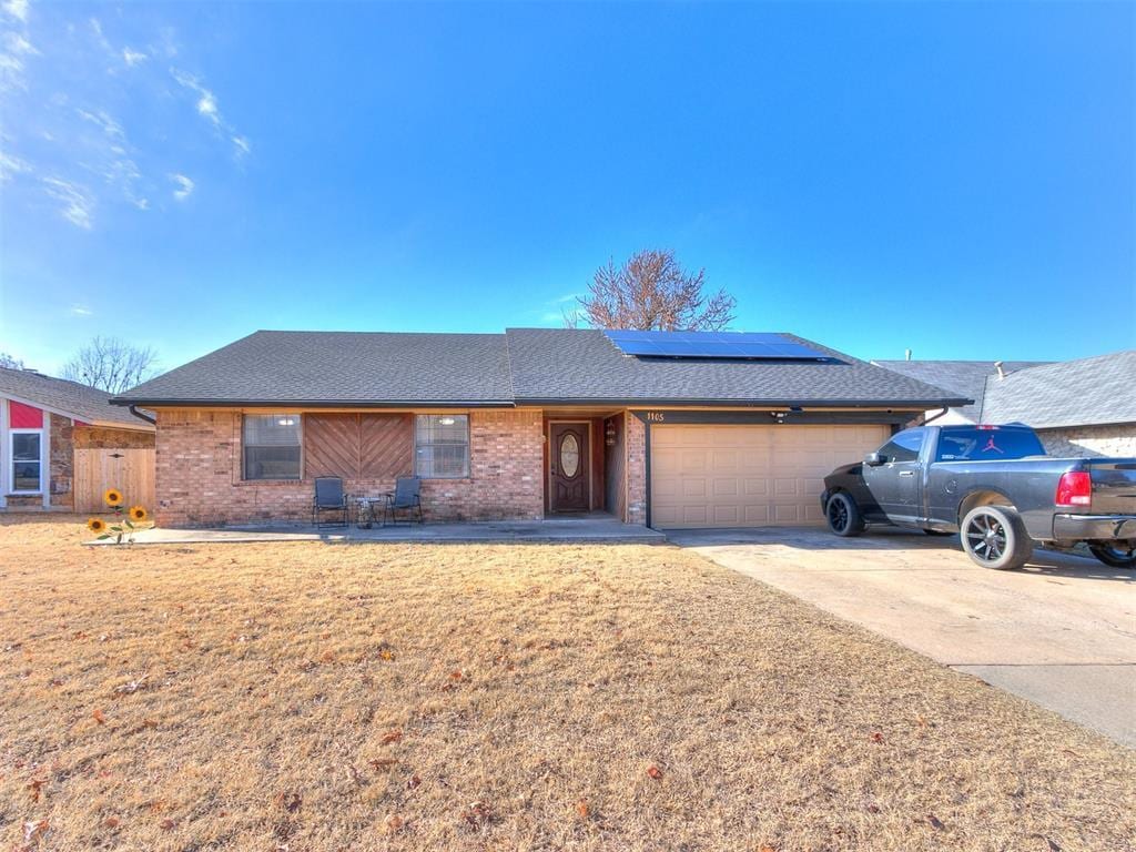 single story home with solar panels and a garage