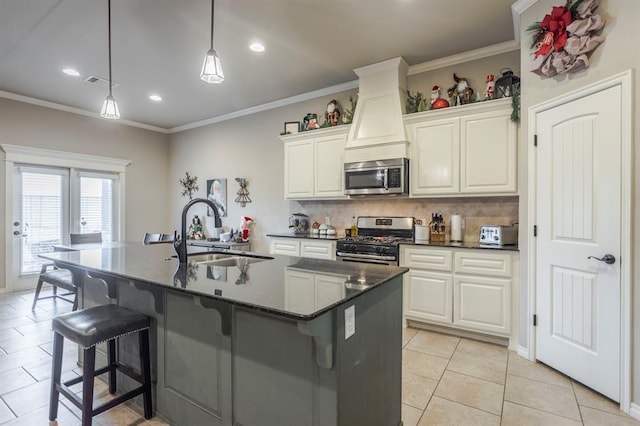 kitchen with backsplash, stainless steel appliances, sink, light tile patterned floors, and an island with sink