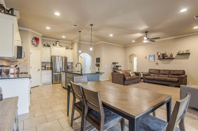 tiled dining area featuring ceiling fan, ornamental molding, and sink