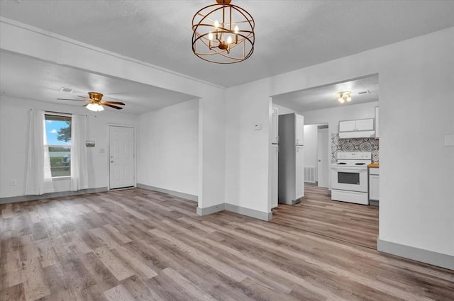 unfurnished living room with ceiling fan with notable chandelier and light hardwood / wood-style flooring