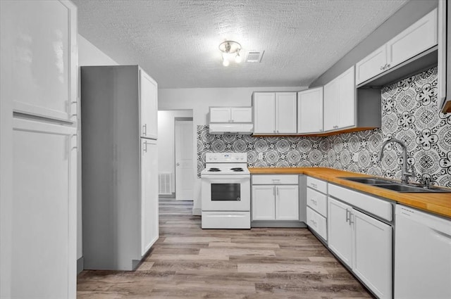 kitchen with butcher block counters, sink, backsplash, white appliances, and white cabinets