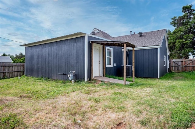 rear view of house featuring central AC and a lawn