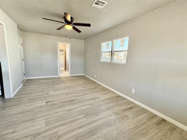 unfurnished bedroom featuring ceiling fan, a walk in closet, and light wood-type flooring