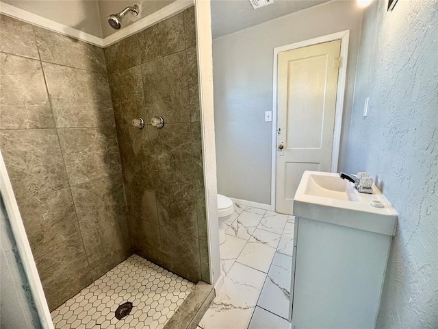 bathroom featuring toilet, tiled shower, and vanity