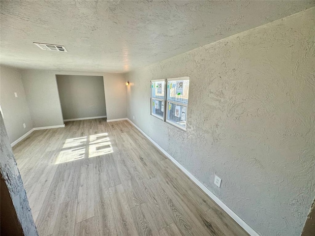 unfurnished room featuring a textured ceiling and light hardwood / wood-style flooring