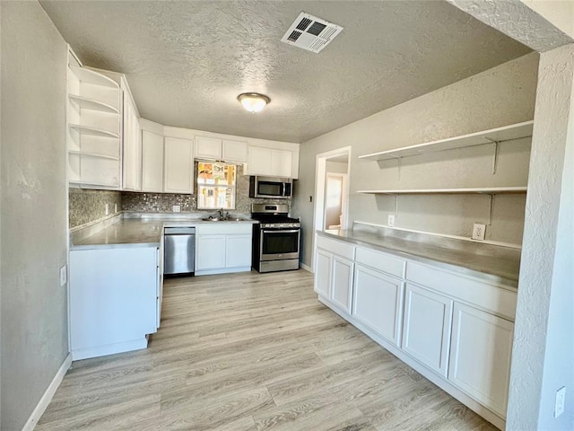 kitchen featuring stainless steel counters, light hardwood / wood-style floors, sink, appliances with stainless steel finishes, and white cabinets