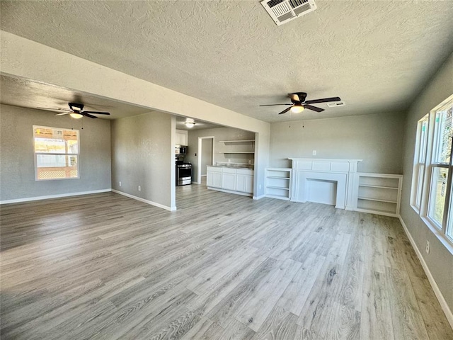 unfurnished living room featuring a textured ceiling and light hardwood / wood-style flooring