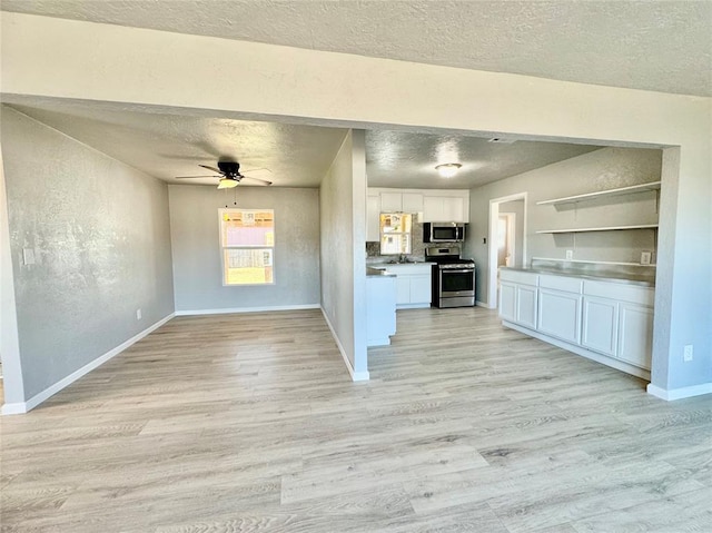 kitchen featuring white cabinets, stainless steel appliances, decorative backsplash, light wood-type flooring, and ceiling fan