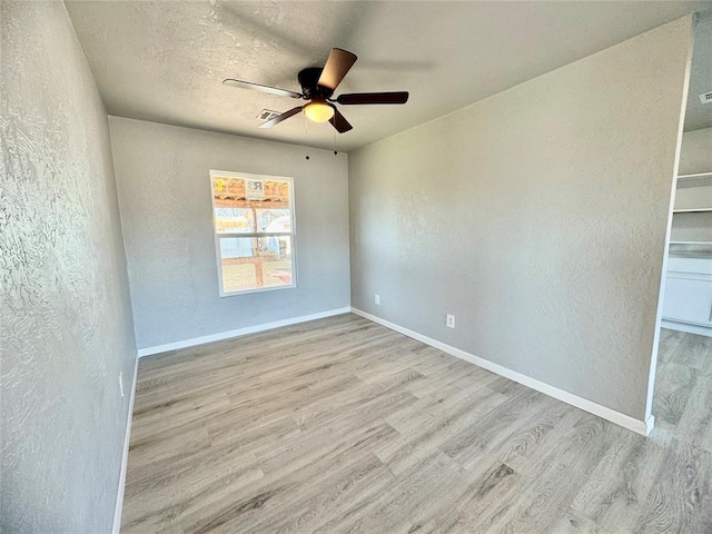 spare room with ceiling fan, light wood-type flooring, and a textured ceiling