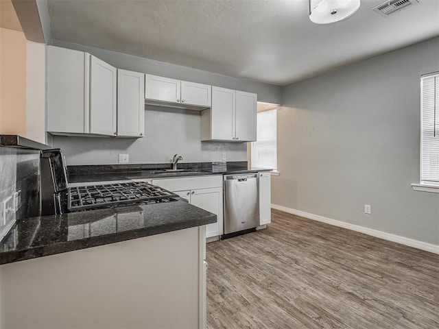 kitchen with white cabinetry, stainless steel dishwasher, a healthy amount of sunlight, and sink