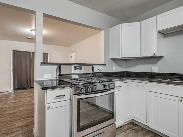 kitchen with white cabinets, dark stone countertops, dark wood-type flooring, and stainless steel range with gas stovetop