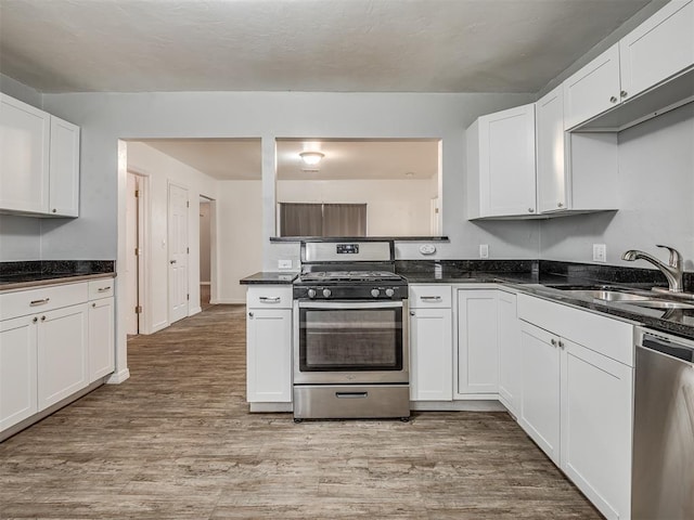 kitchen featuring white cabinetry, sink, light hardwood / wood-style flooring, and appliances with stainless steel finishes