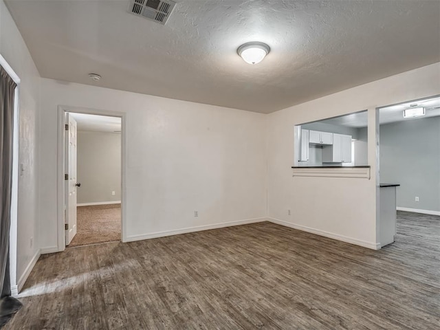 spare room featuring dark hardwood / wood-style flooring and a textured ceiling