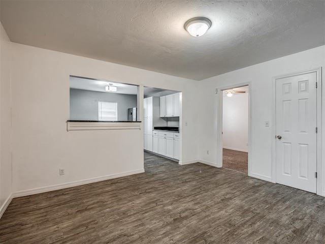 unfurnished living room featuring ceiling fan, dark hardwood / wood-style flooring, and a textured ceiling